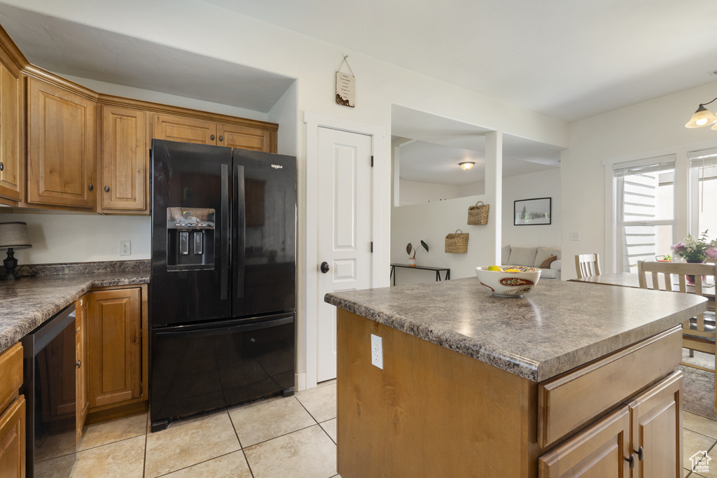Kitchen featuring black refrigerator with ice dispenser, dishwashing machine, dark countertops, and light tile patterned flooring