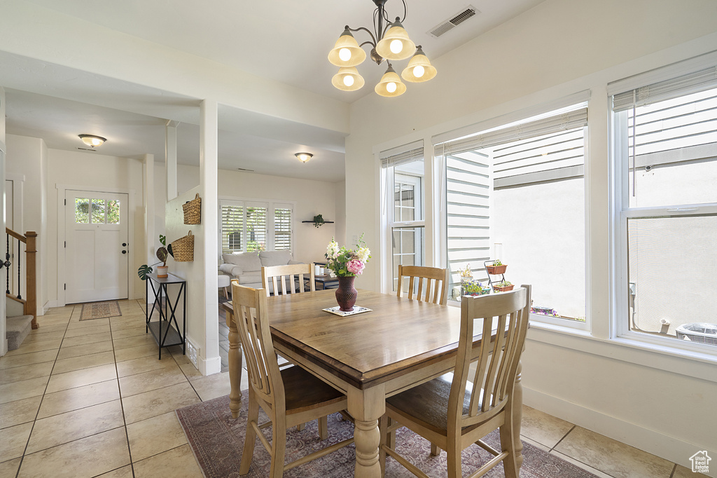 Dining room with light tile patterned floors, a chandelier, and stairway