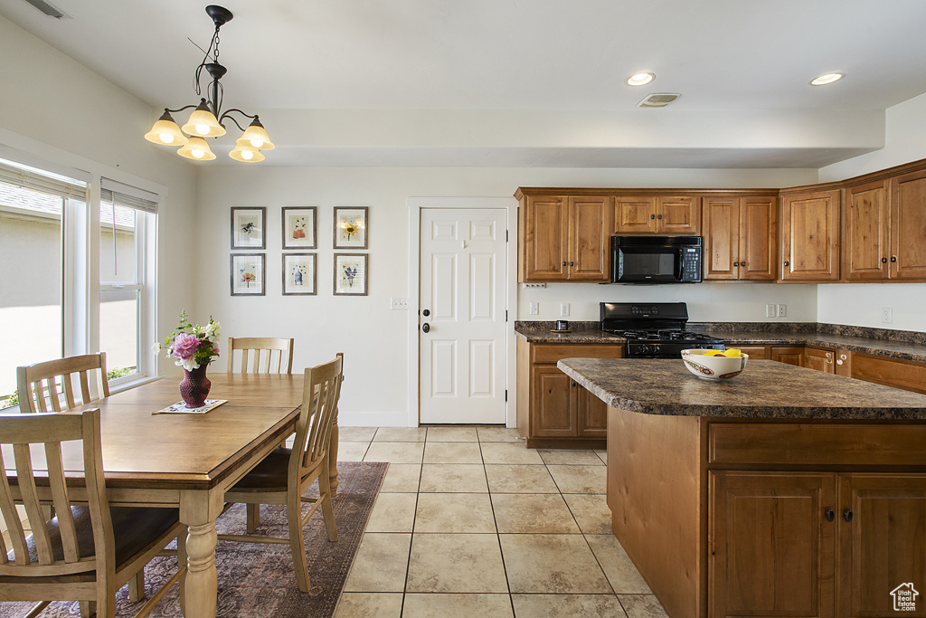 Kitchen featuring black appliances, brown cabinets, a chandelier, dark countertops, and light tile patterned floors