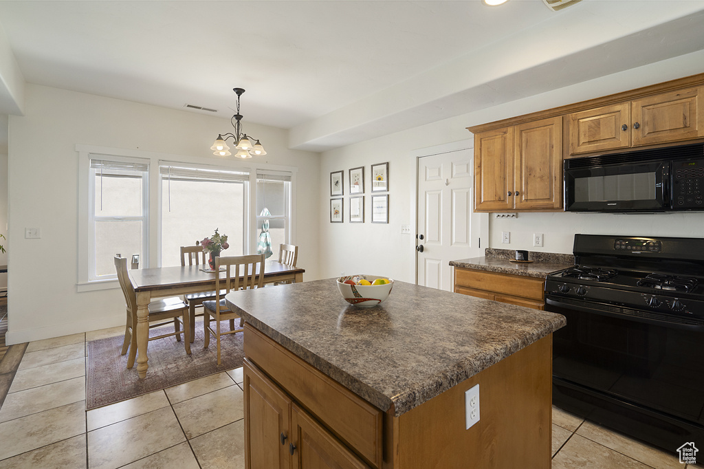 Kitchen featuring black appliances, dark countertops, brown cabinets, a center island, and light tile patterned flooring