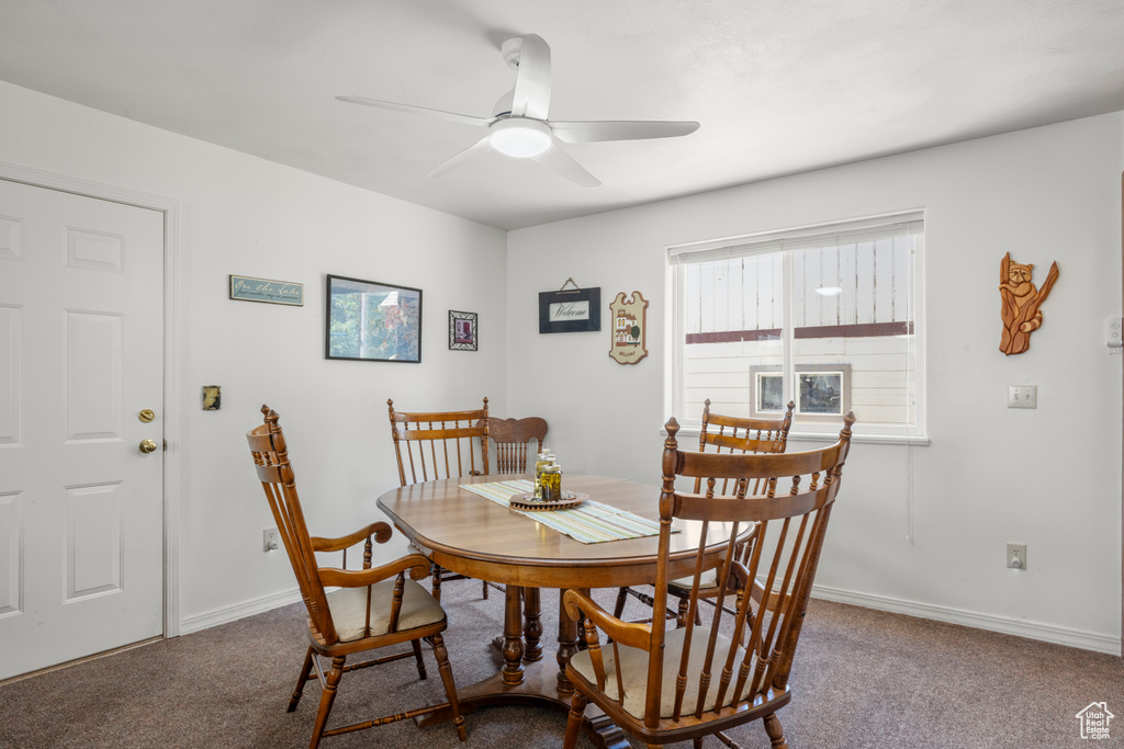 Carpeted dining space with a ceiling fan and baseboards