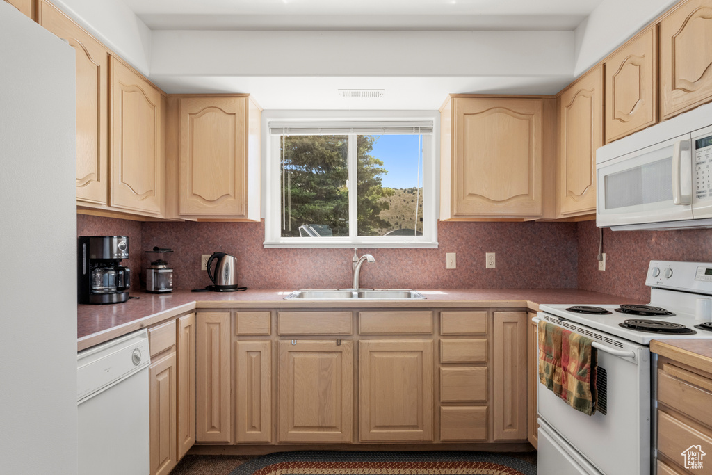 Kitchen with white appliances, light brown cabinets, light countertops, and decorative backsplash