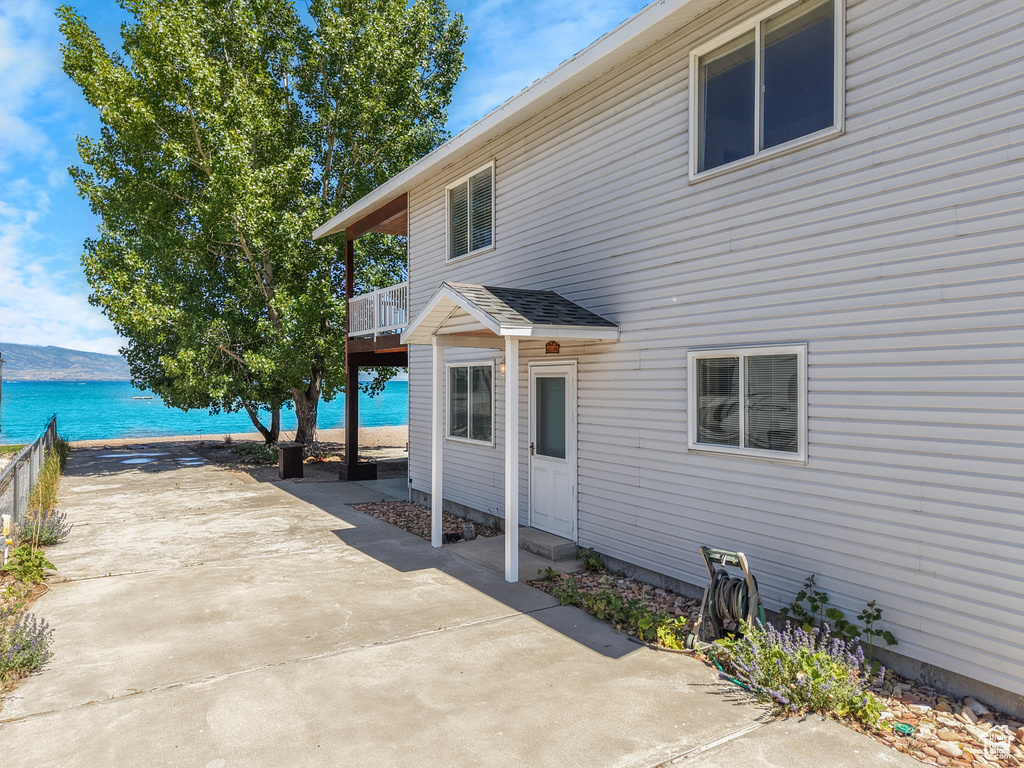 Rear view of house featuring a patio area, a balcony, and a water view