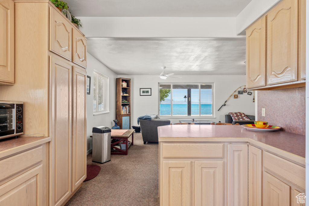 Kitchen with carpet flooring, a peninsula, light brown cabinetry, and a ceiling fan