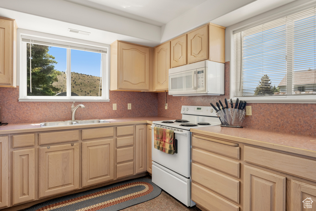 Kitchen with white appliances, light brown cabinets, light countertops, and tasteful backsplash