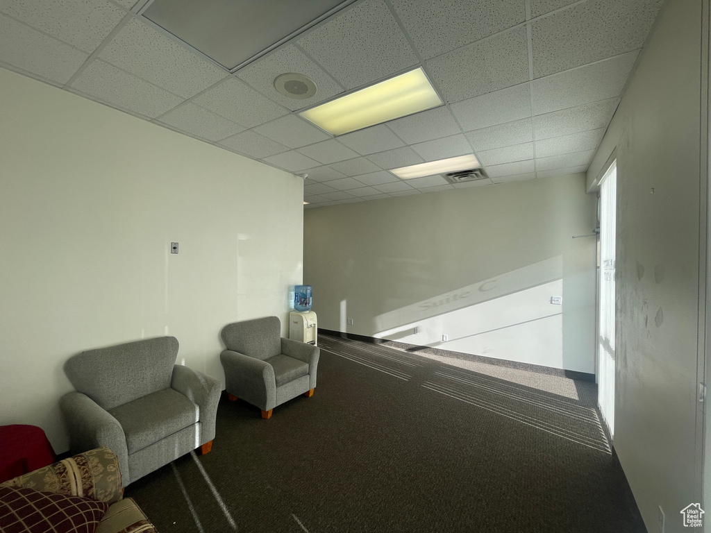 Living area featuring a paneled ceiling and baseboards