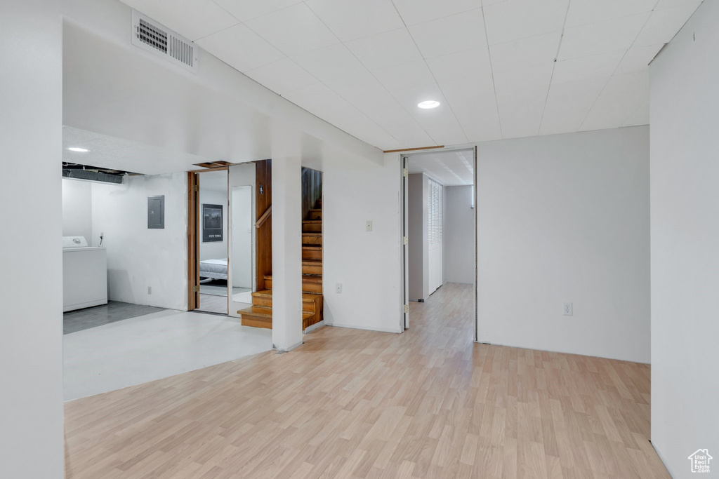 Spare room featuring washer / clothes dryer, electric panel, wood finished floors, stairs, and recessed lighting