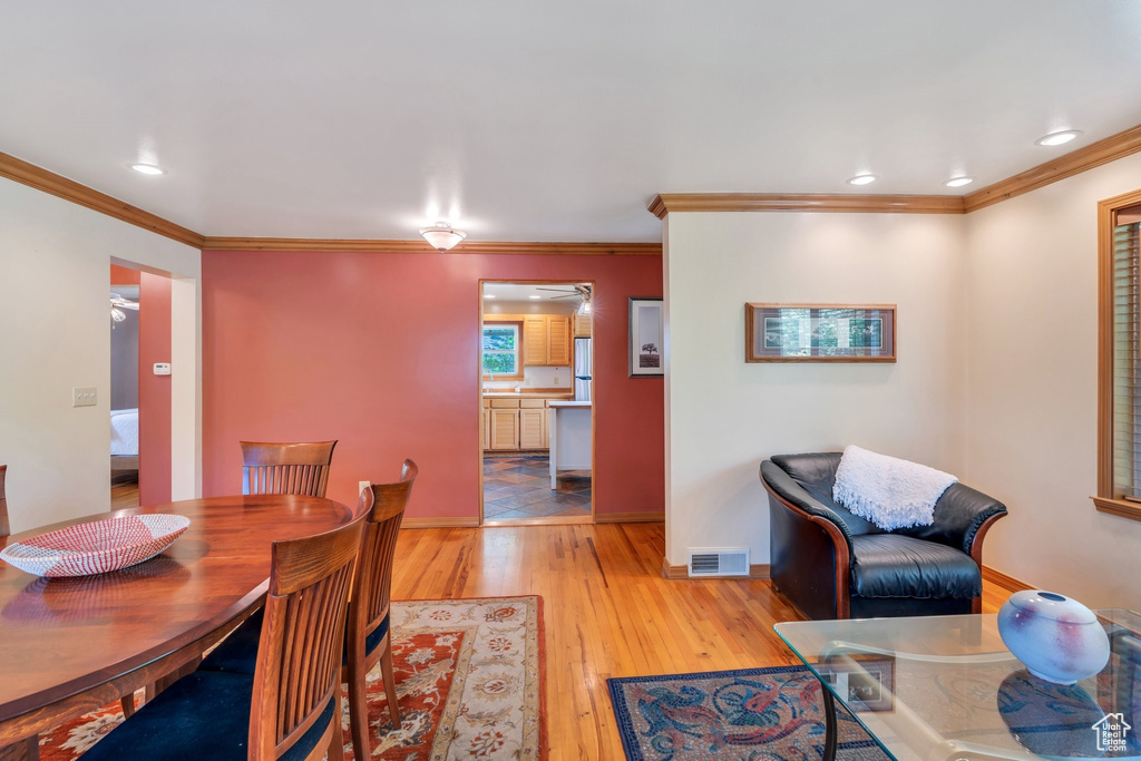 Dining room with ornamental molding, light wood-style flooring, and recessed lighting