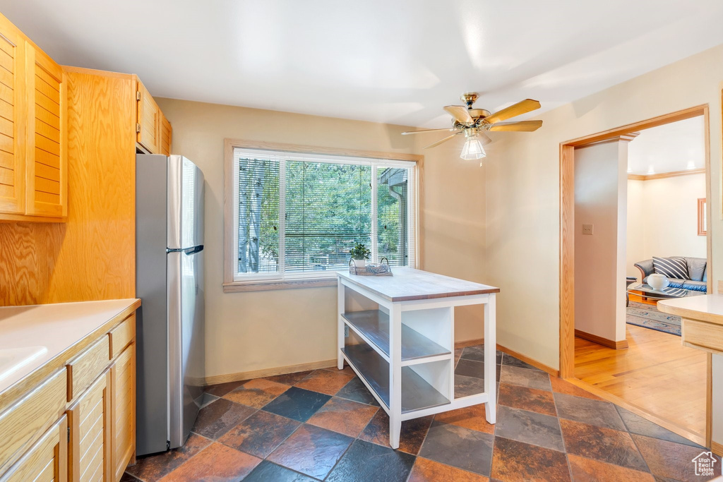 Kitchen with freestanding refrigerator, stone tile floors, and light countertops