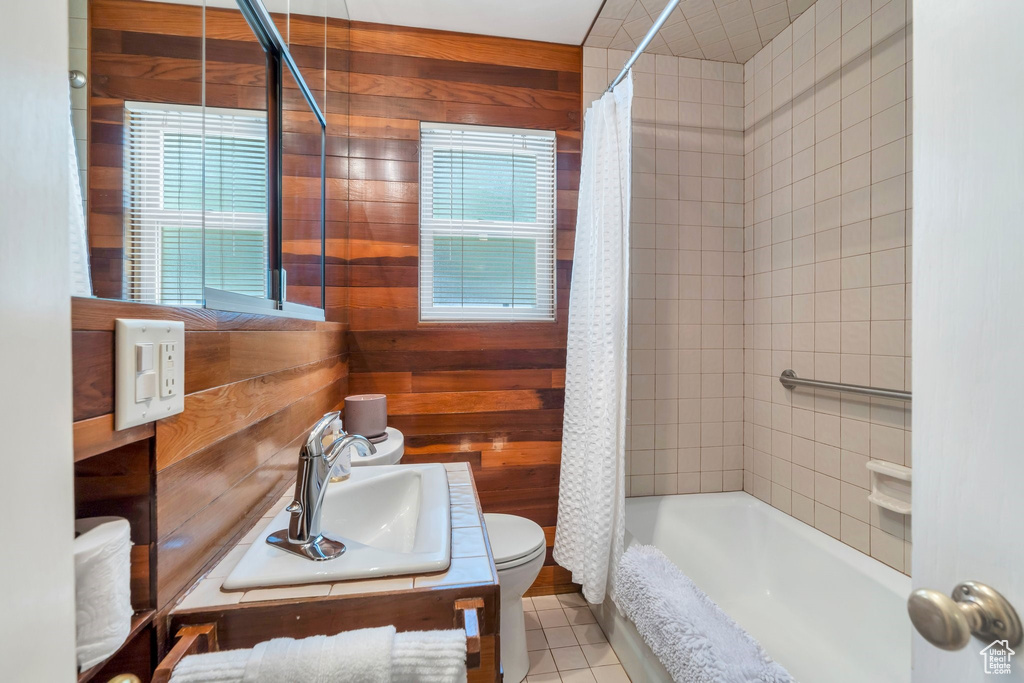Bathroom with wood walls, vanity, shower / tub combo with curtain, and tile patterned flooring