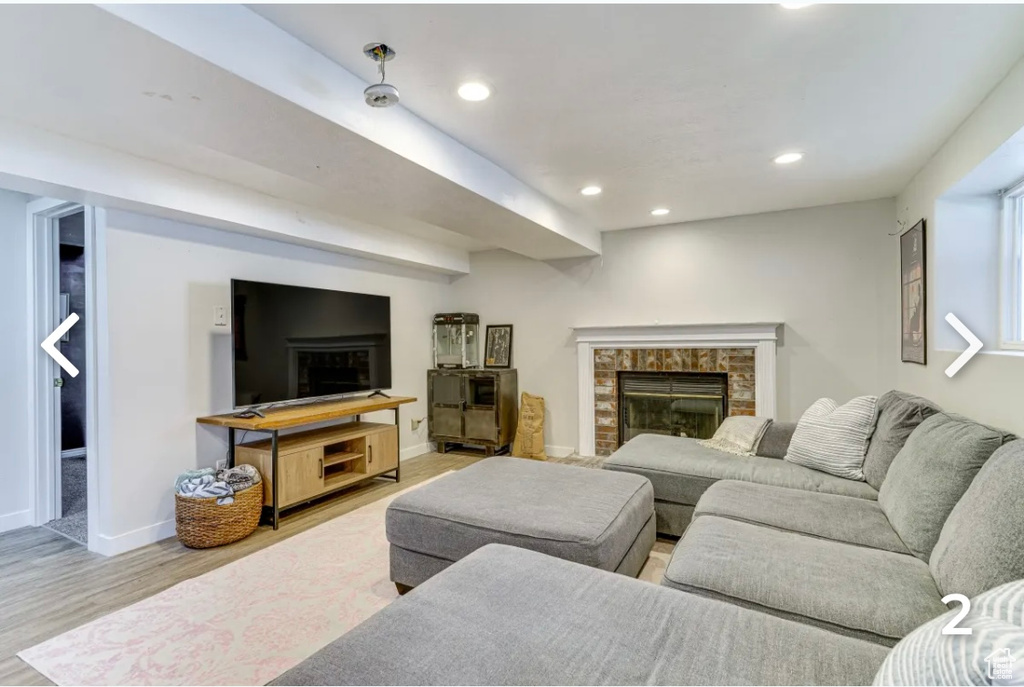 Living area featuring a brick fireplace, wood finished floors, and recessed lighting