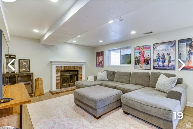 Living area with wood finished floors, recessed lighting, and a brick fireplace