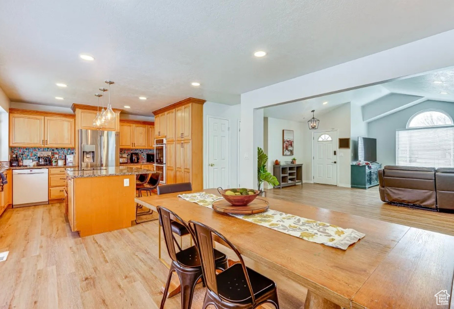 Dining room with light wood-style floors, lofted ceiling, and recessed lighting