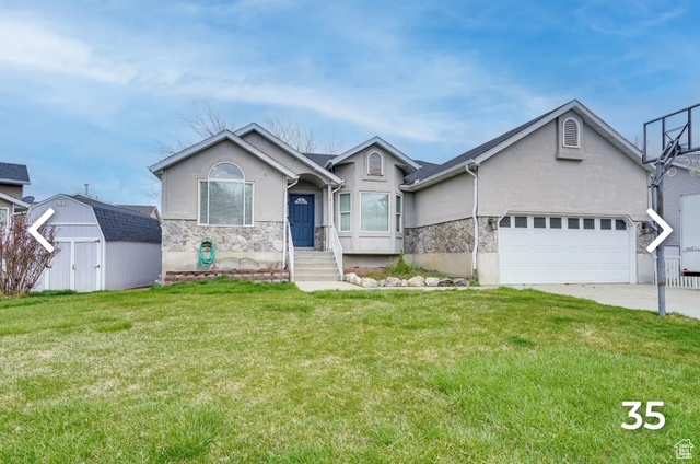 Single story home with stucco siding, stone siding, a storage shed, and a front lawn