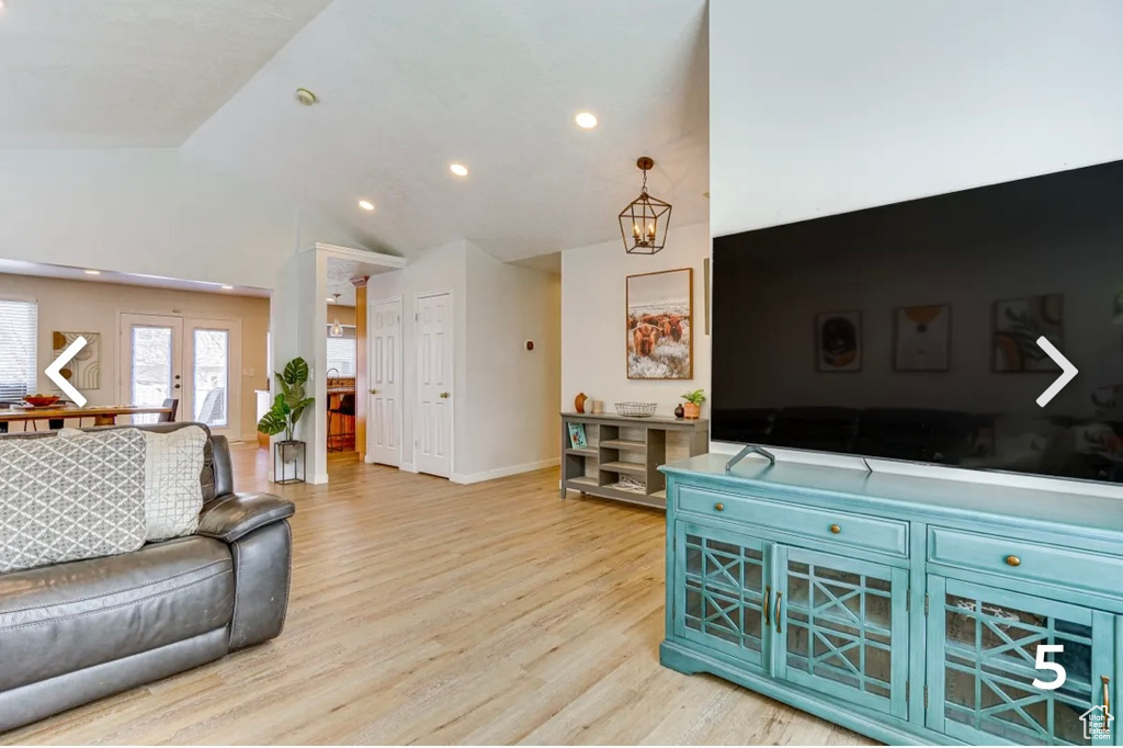 Living area featuring light wood-type flooring, recessed lighting, a chandelier, high vaulted ceiling, and french doors