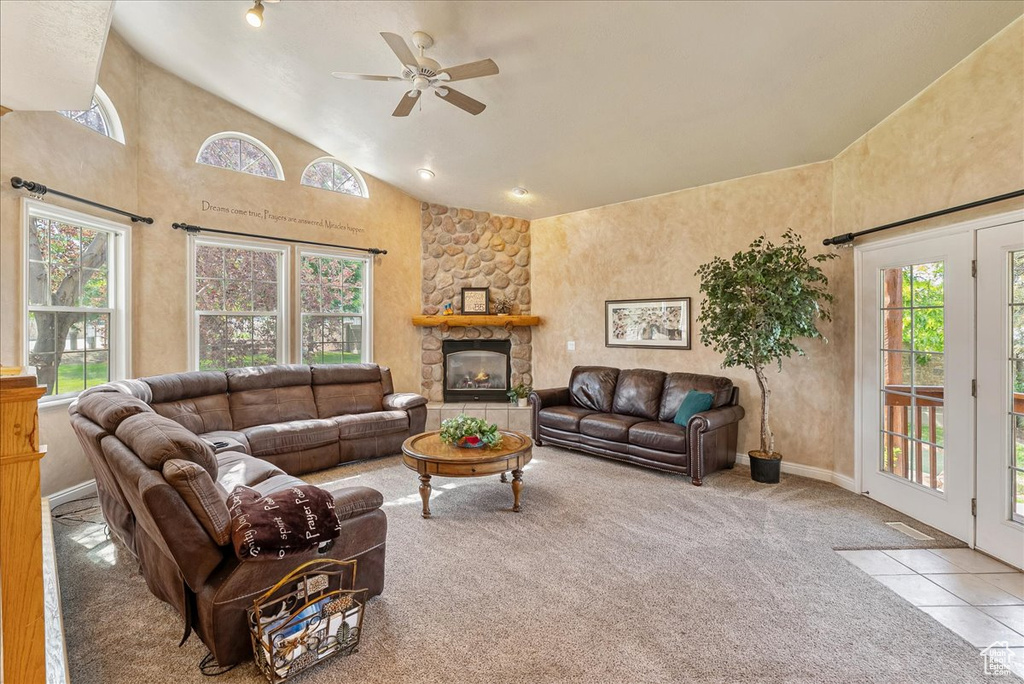 Carpeted living area with healthy amount of natural light, a ceiling fan, high vaulted ceiling, and a fireplace
