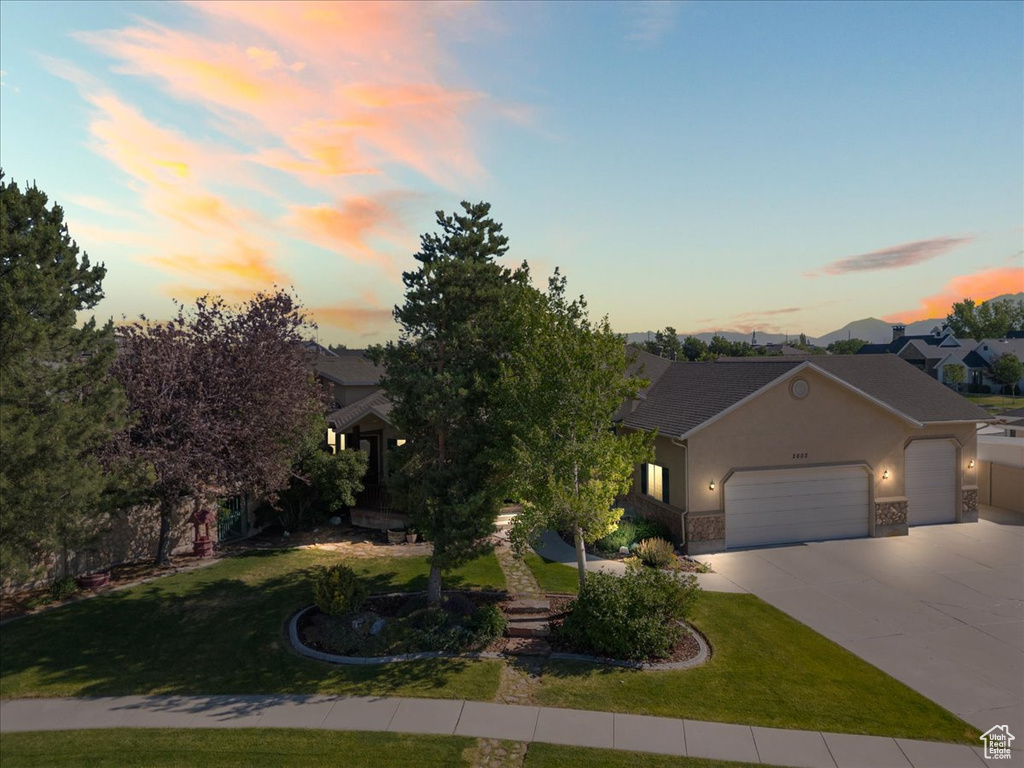View of front of home featuring a garage, stucco siding, a front yard, and driveway