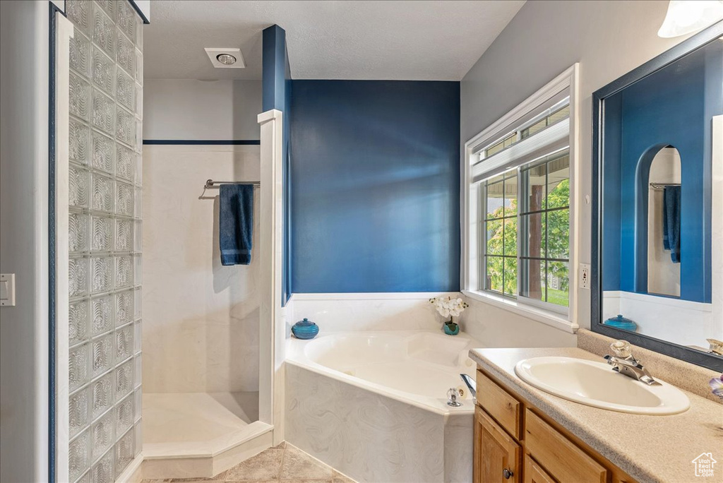 Full bath with a garden tub, vanity, walk in shower, and tile patterned floors