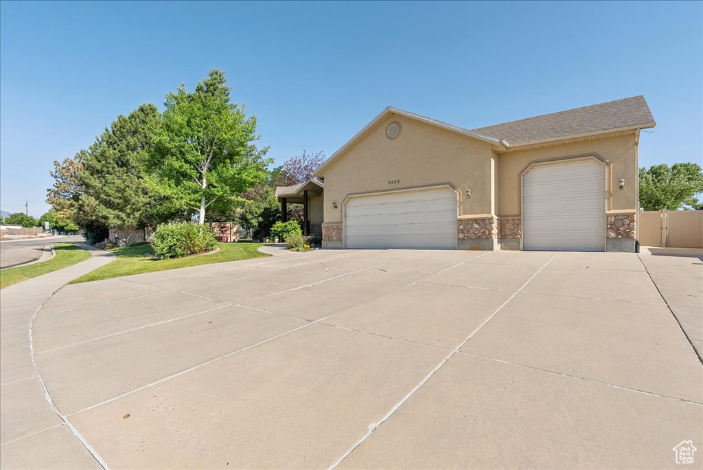 Townhome / multi-family property featuring driveway, a garage, stucco siding, and stone siding