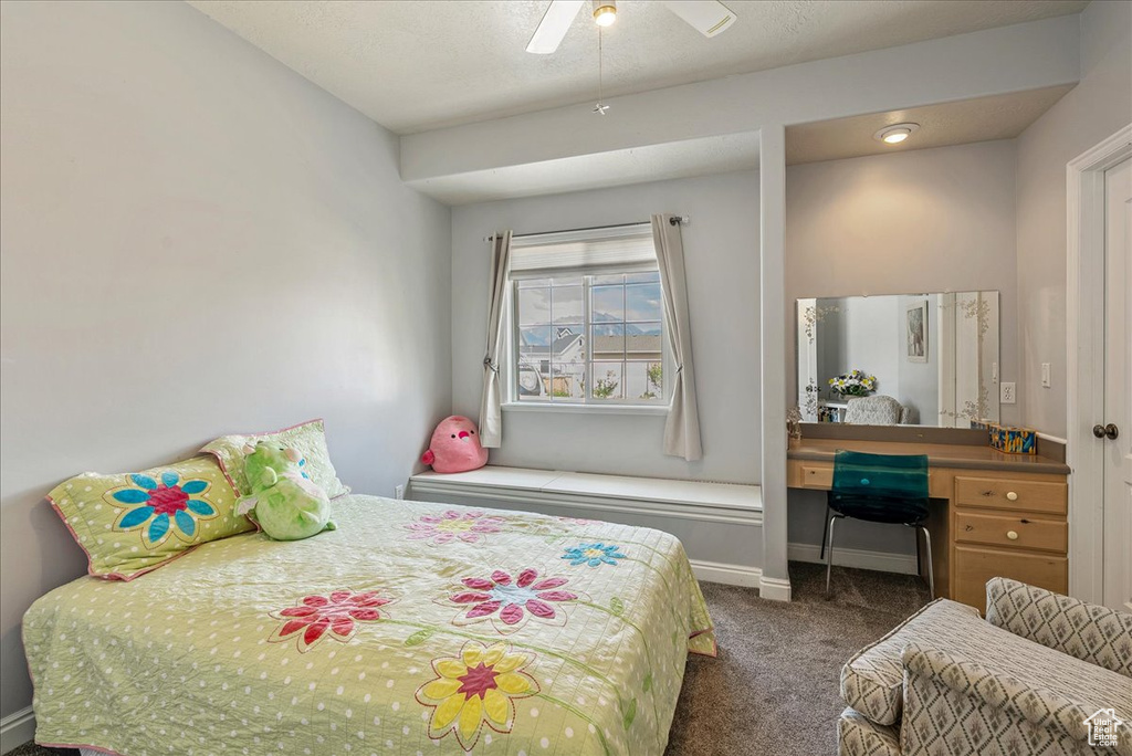 Bedroom with dark carpet, a desk, and a ceiling fan