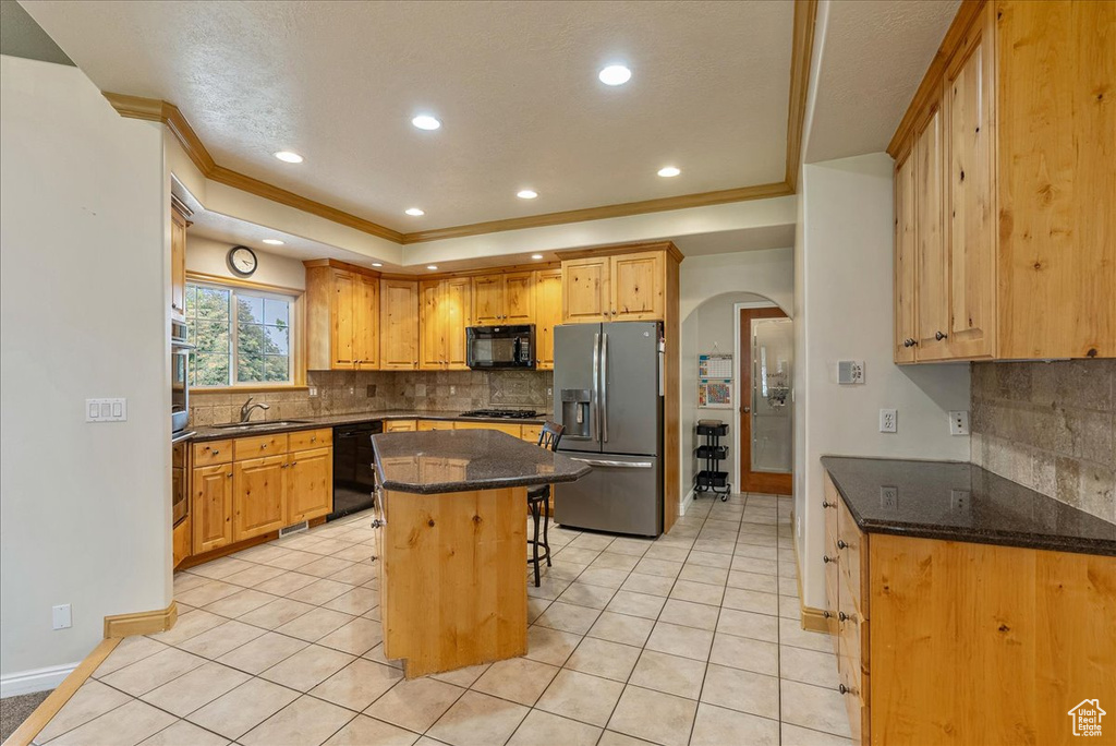 Kitchen featuring black appliances, arched walkways, tasteful backsplash, a breakfast bar area, and recessed lighting