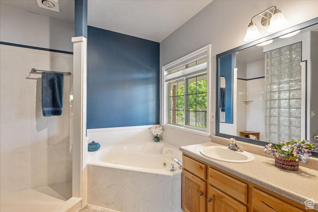 Bathroom with a whirlpool tub, walk in shower, and vanity