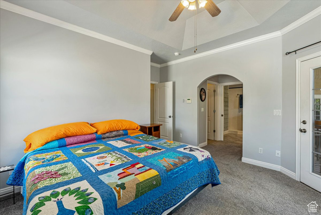 Carpeted bedroom with arched walkways, crown molding, and ceiling fan