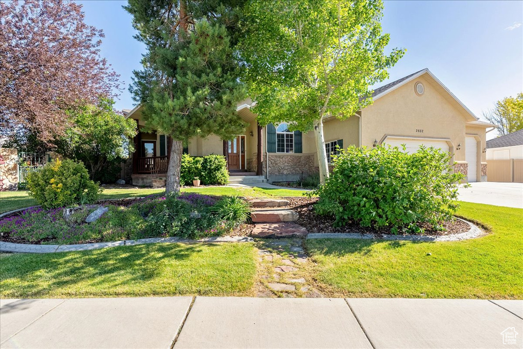 Obstructed view of property with an attached garage, a front yard, stucco siding, and driveway