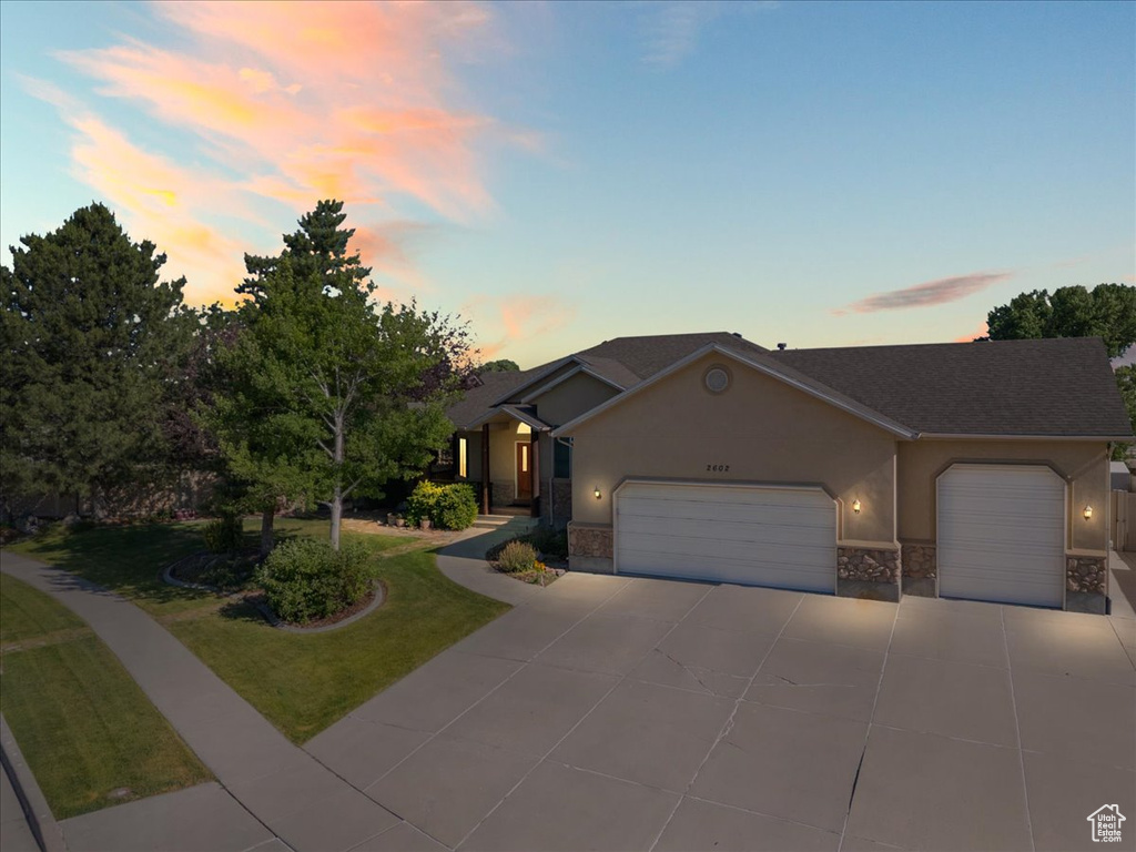 Single story home featuring a garage, driveway, stucco siding, a front yard, and stone siding
