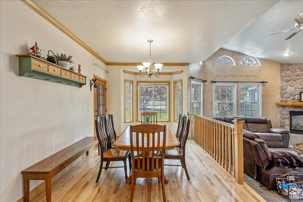 Dining area featuring light wood finished floors, plenty of natural light, a chandelier, a textured ceiling, and lofted ceiling