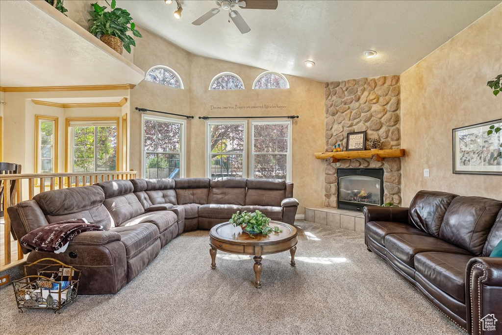 Carpeted living room featuring a ceiling fan, vaulted ceiling, and a tile fireplace