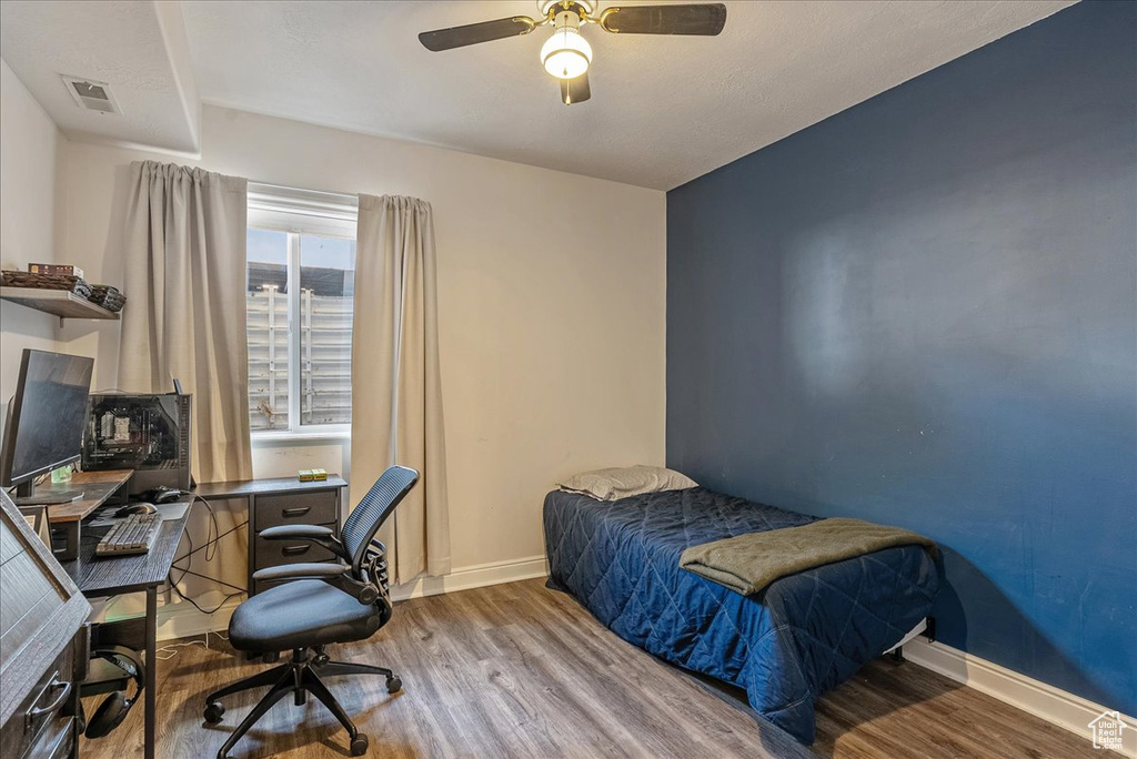 Bedroom featuring wood finished floors, a desk, and a ceiling fan
