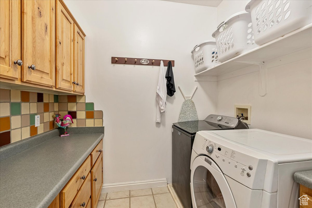 Laundry area with washer and dryer, light tile patterned floors, and cabinet space