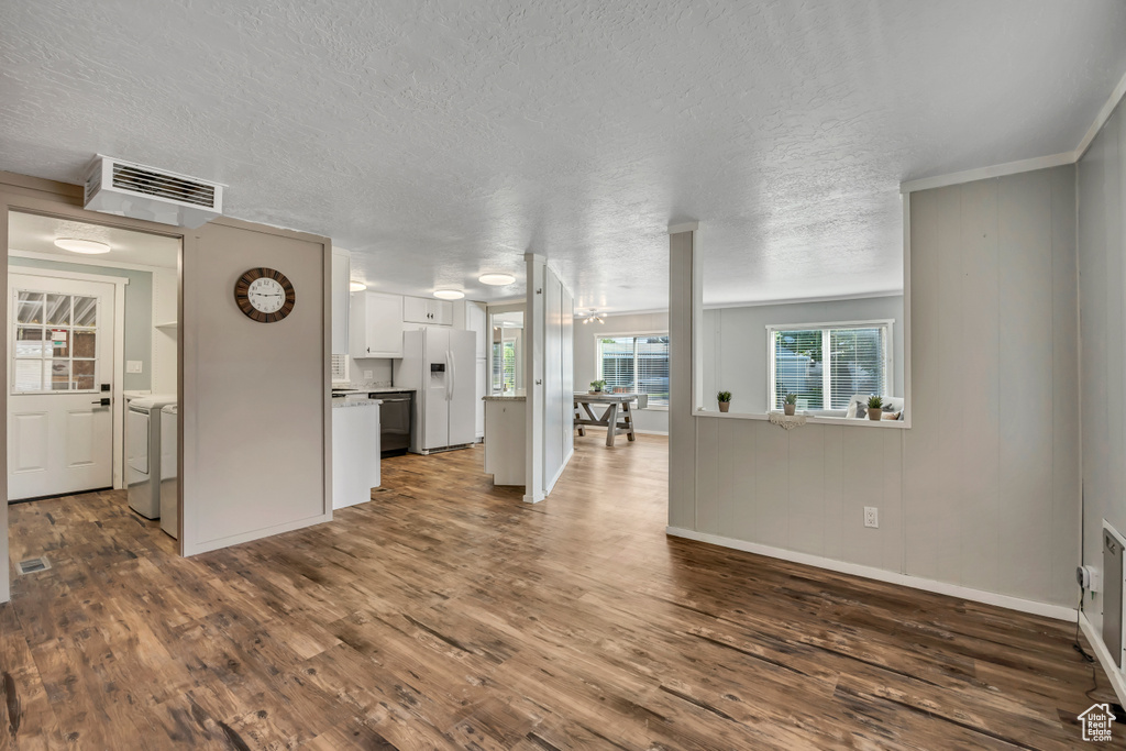 Unfurnished living room with dark wood-type flooring, a textured ceiling, and washing machine and dryer