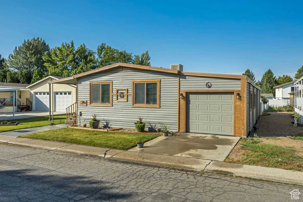View of front of property featuring a garage, driveway, and a front yard