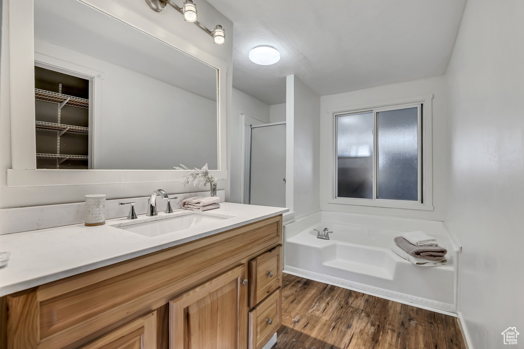 Bathroom with a bath, vanity, a shower stall, and wood finished floors