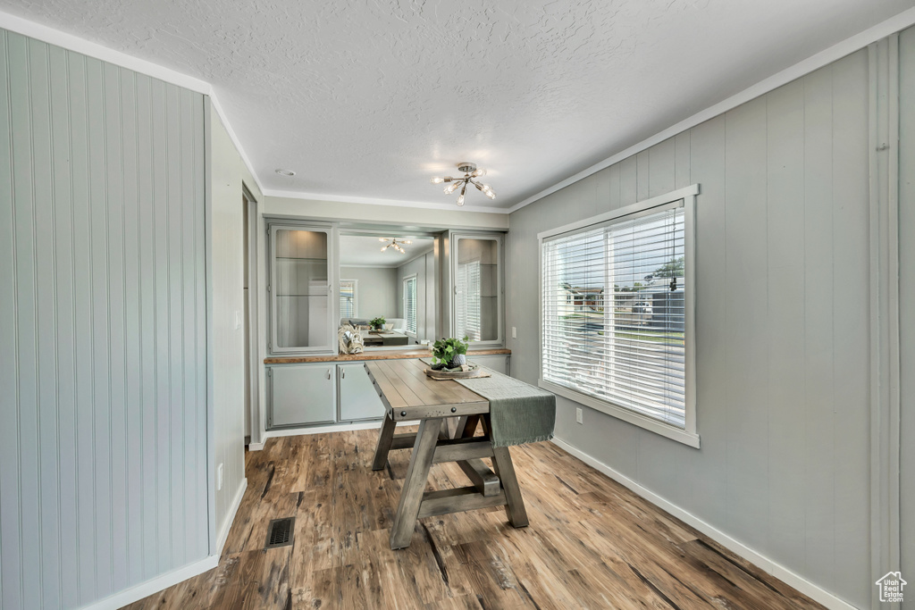 Dining area featuring ornamental molding, a chandelier, wood finished floors, and a textured ceiling