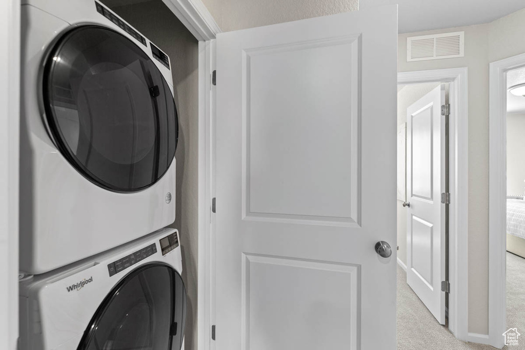 Washroom featuring stacked washer / dryer and carpet