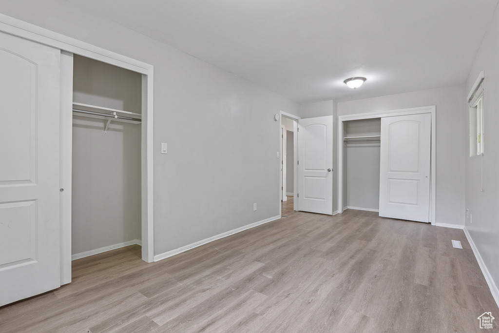Unfurnished bedroom with two closets and light wood-style flooring