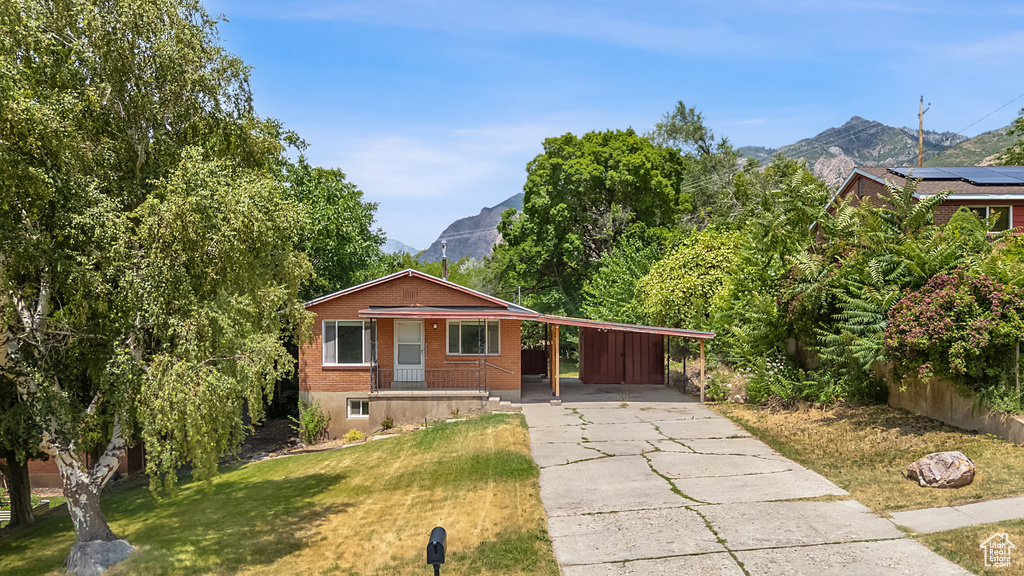Single story home with a carport, a mountain view, and a front yard