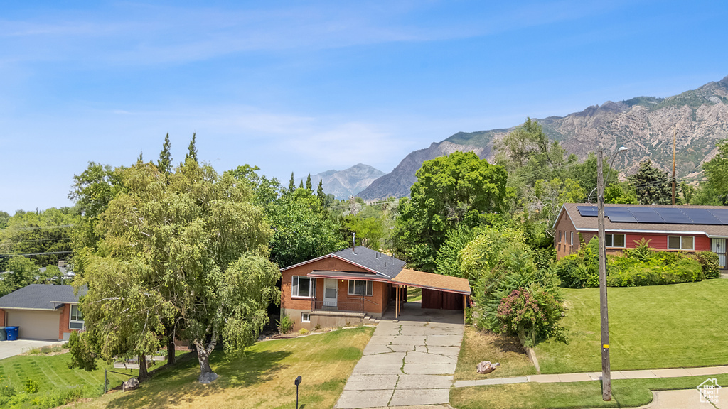 Single story home with concrete driveway, a front yard, a carport, and a mountain view