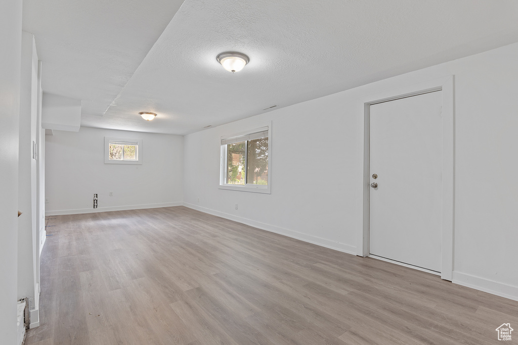 Empty room with light wood-style floors and a textured ceiling