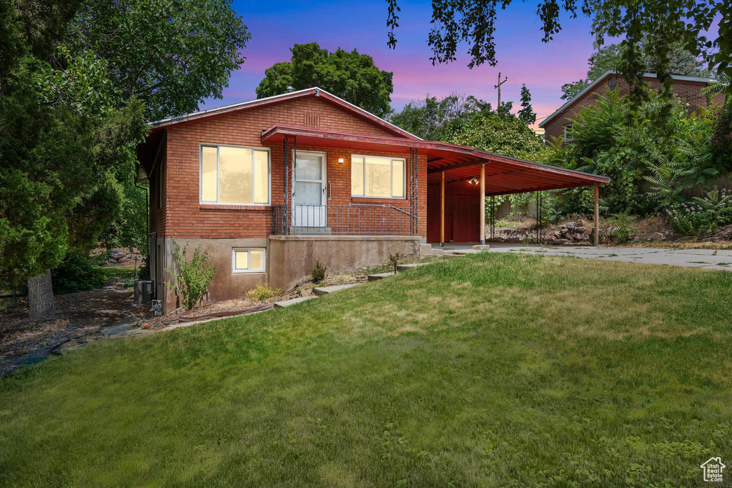 View of front facade with a front lawn, an attached carport, and concrete driveway