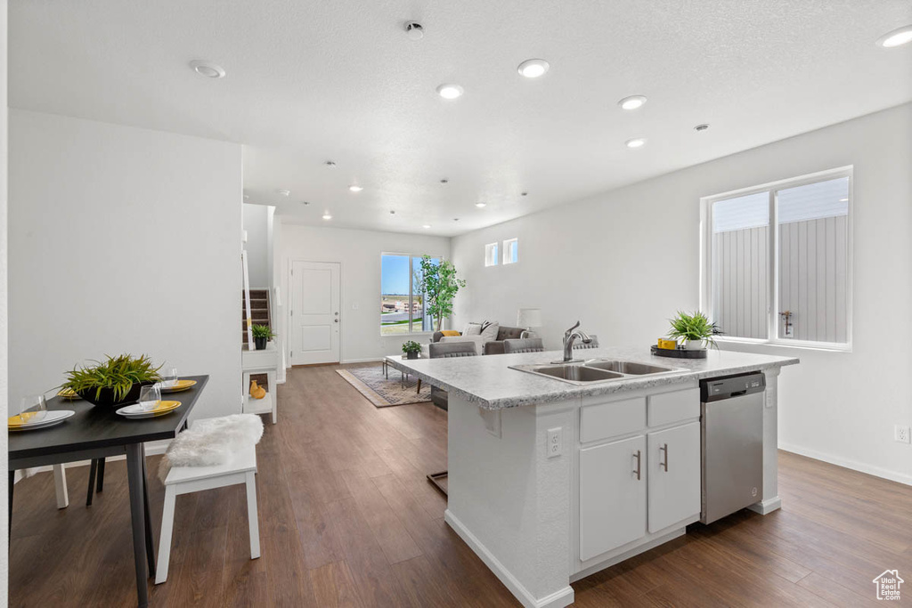 Kitchen featuring dishwasher, a kitchen island with sink, light countertops, dark wood-style flooring, and recessed lighting