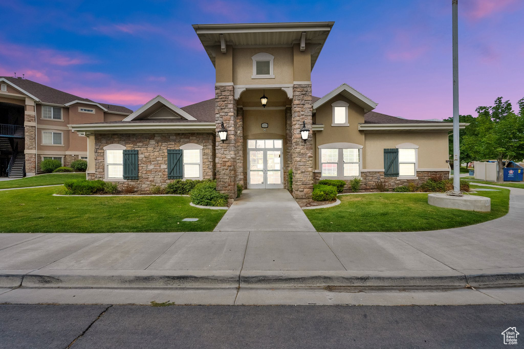 View of front of home featuring stucco siding, stone siding, french doors, and a front yard