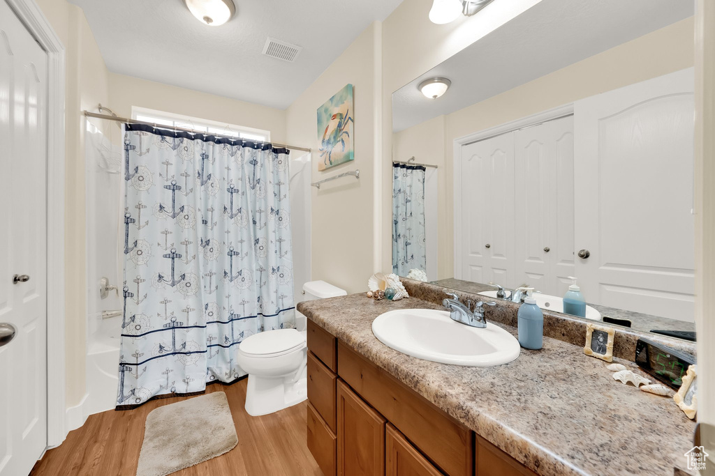Bathroom with wood finished floors, vanity, and shower / tub combo
