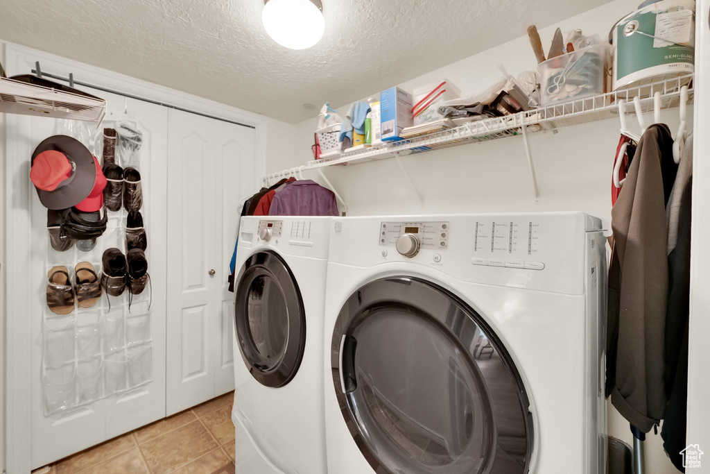 Laundry area with washing machine and dryer, a textured ceiling, and light tile patterned floors
