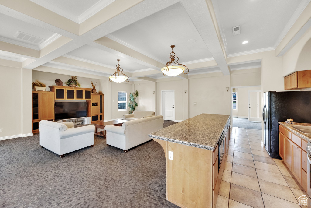 Kitchen with coffered ceiling, beamed ceiling, ornamental molding, black fridge, and a kitchen island