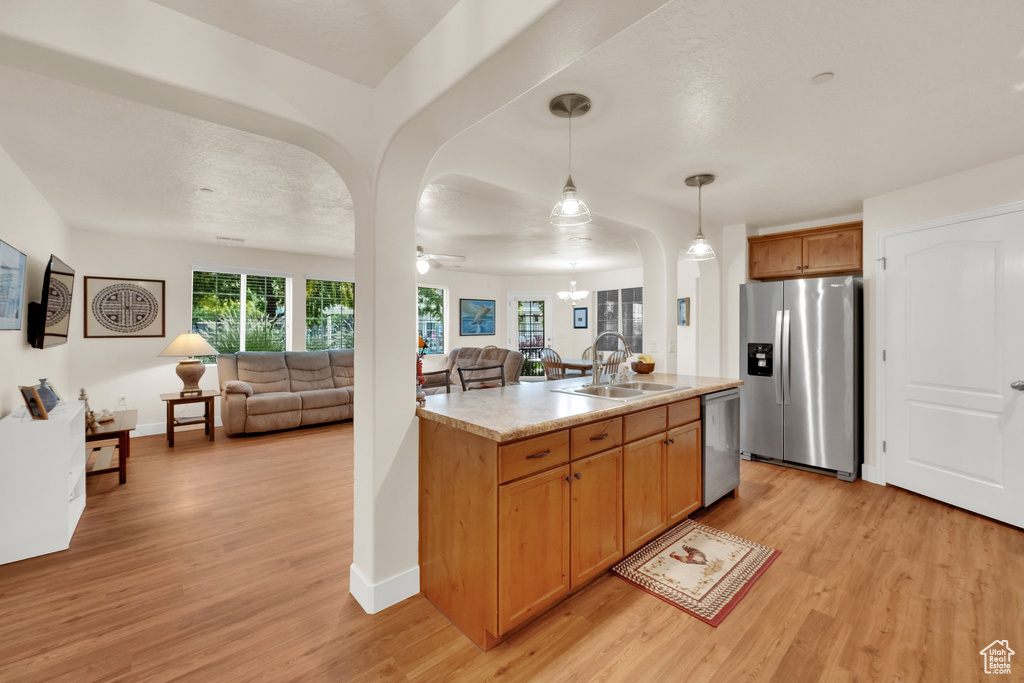 Kitchen featuring stainless steel appliances, open floor plan, light wood-style flooring, and light countertops