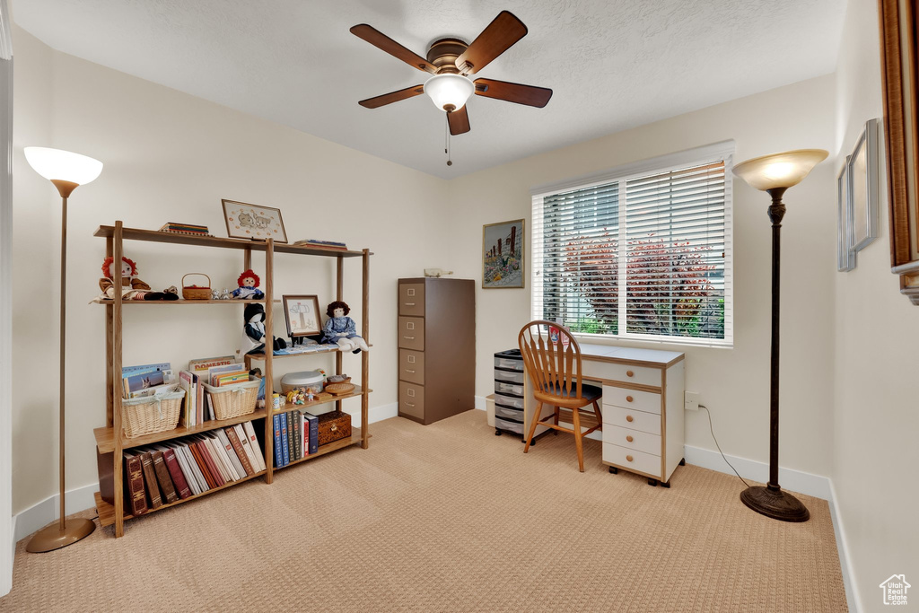 Carpeted home office featuring ceiling fan and baseboards